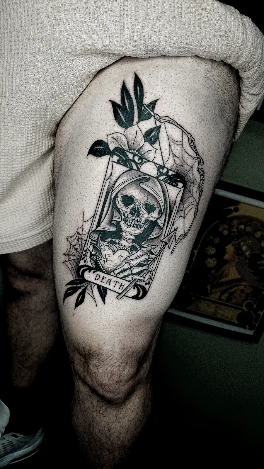 Tatuagem blackwork da carta de tarô da Morte com caveira encapuzada e teia de aranha, na coxa