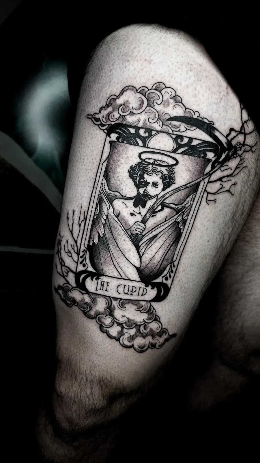 Tatuagem blackwork da carta de tarô do Cupido com anjo e nuvens, na coxa