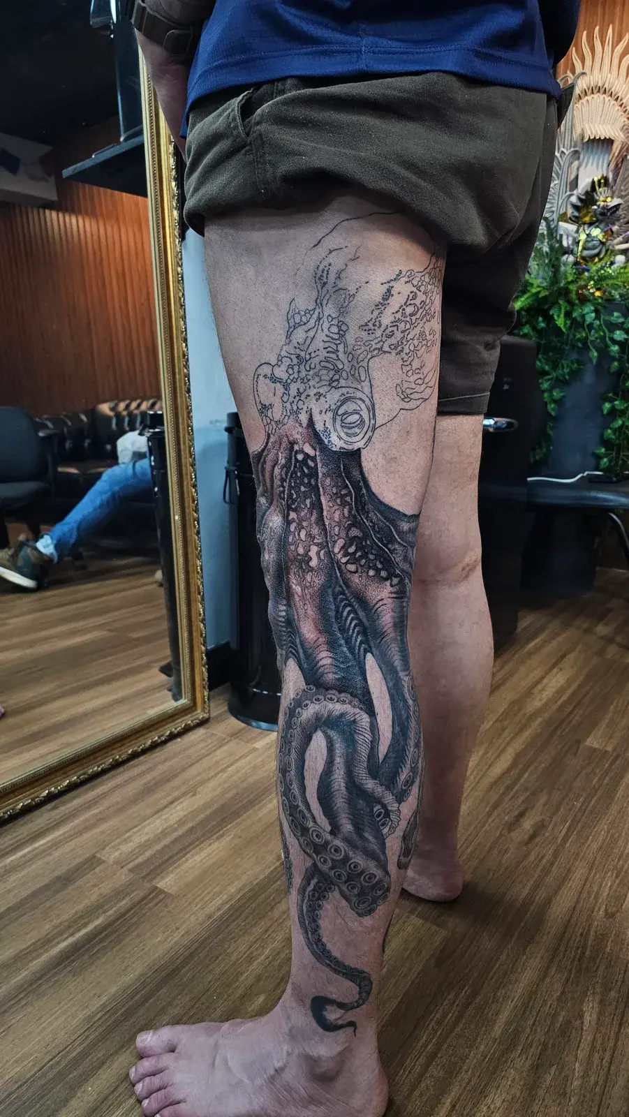 Tatuagem de polvo em preto e cinza em fechamento de perna, da coxa ao tornozelo