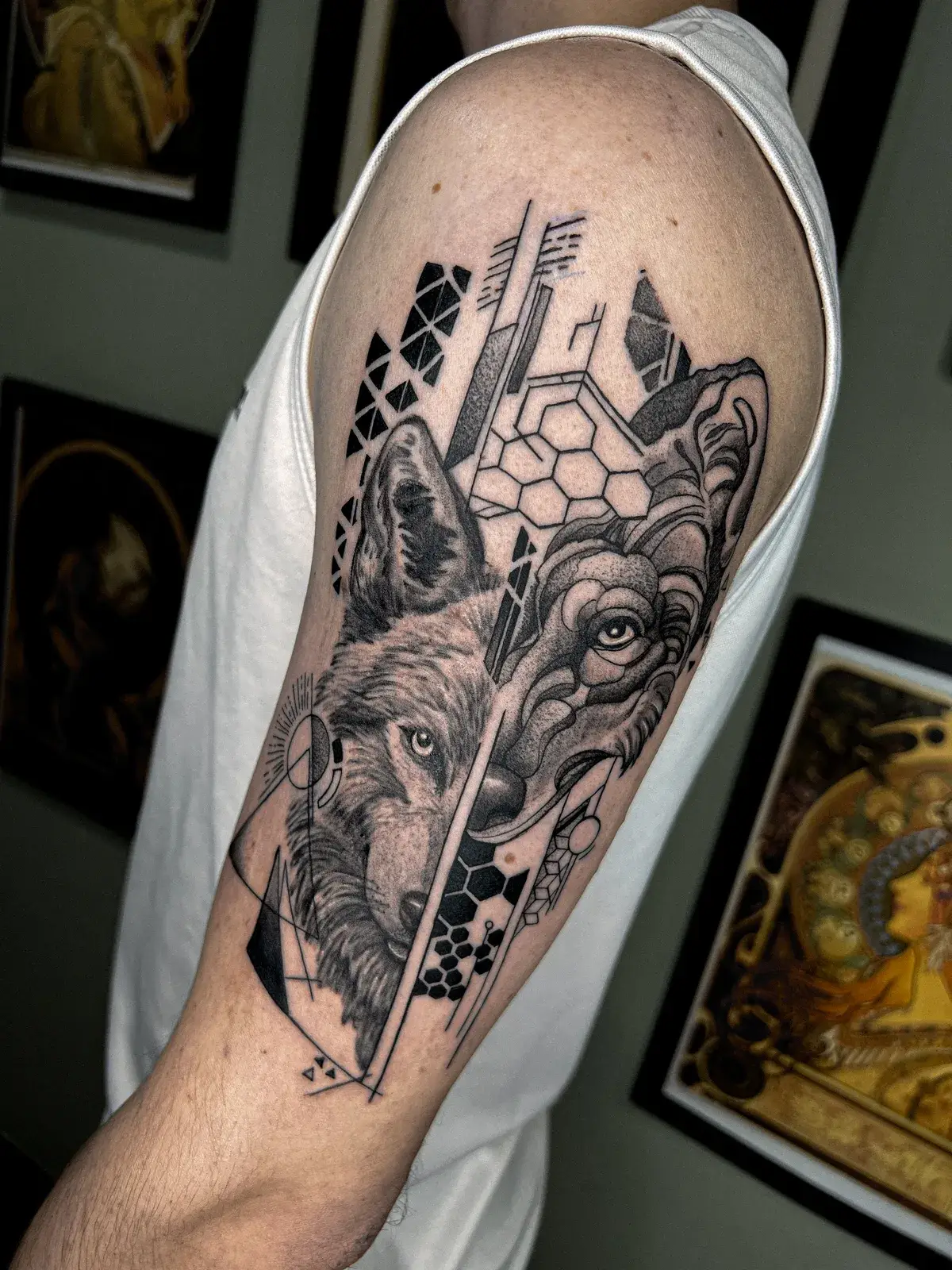 Tatuagem blackwork de lobo dividido entre realismo e formas geométricas no braço