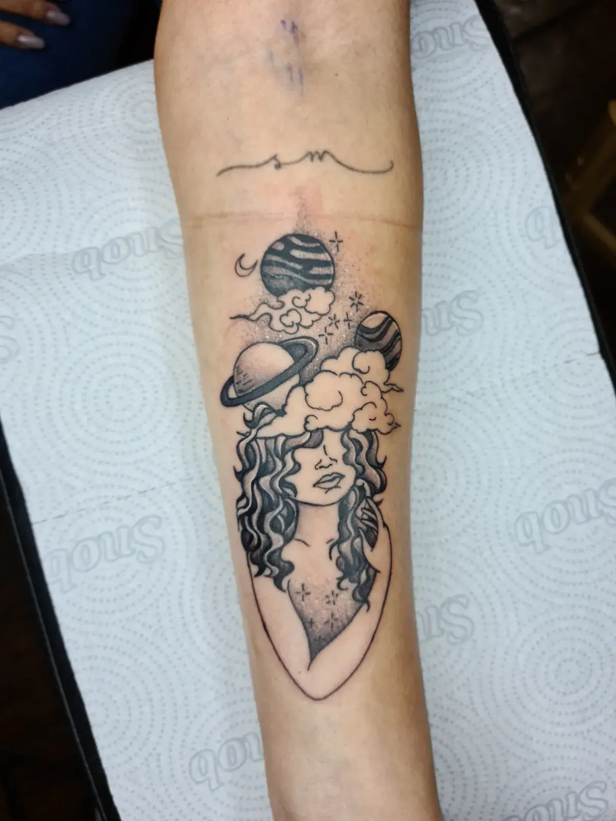 Tatuagem blackwork de mulher com cabelo de nuvens e planetas em pontilhismo no antebraço