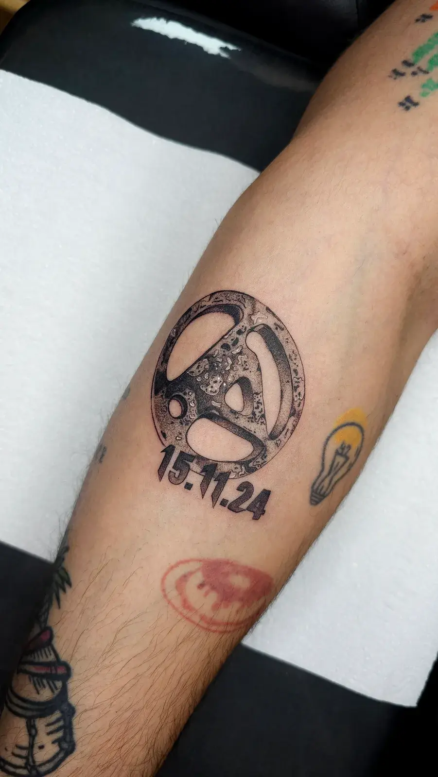 Tatuagem blackwork do símbolo do Linkin Park com uma data, em pontilhismo na panturrilha