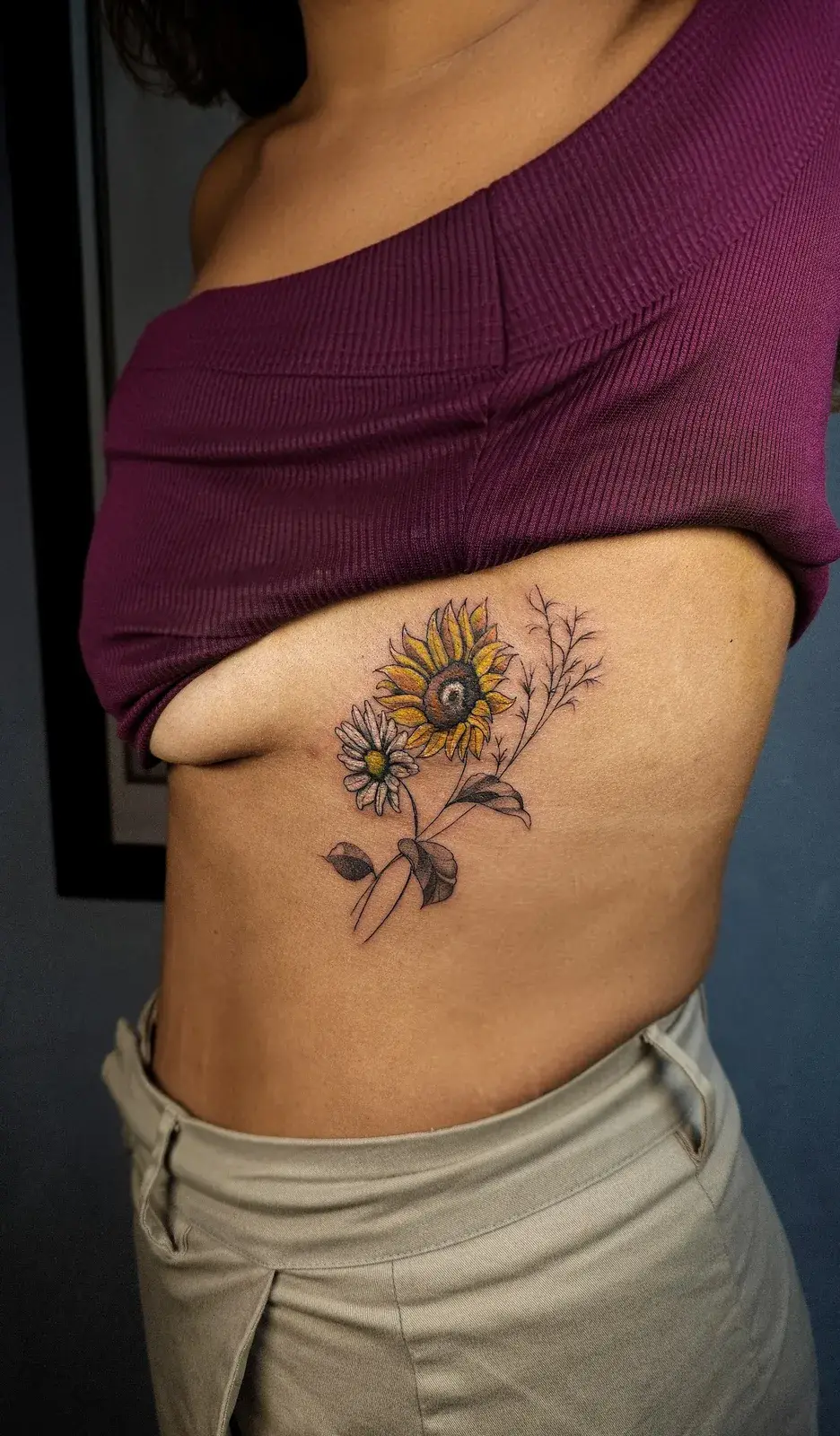Tatuagem de girassol com folhas na lateral da costela