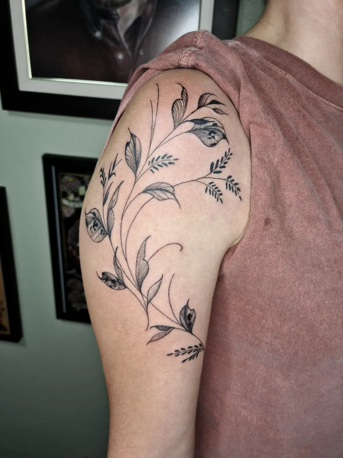 Tatuagem botânica de ramo com folhas descendo do ombro pelo braço