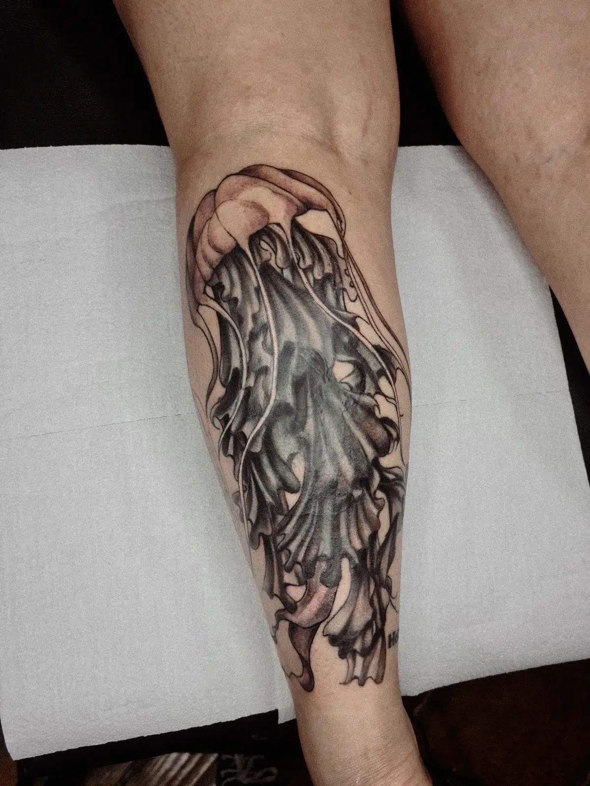Cobertura de tatuagem com água-viva em preto e cinza cobrindo a panturrilha