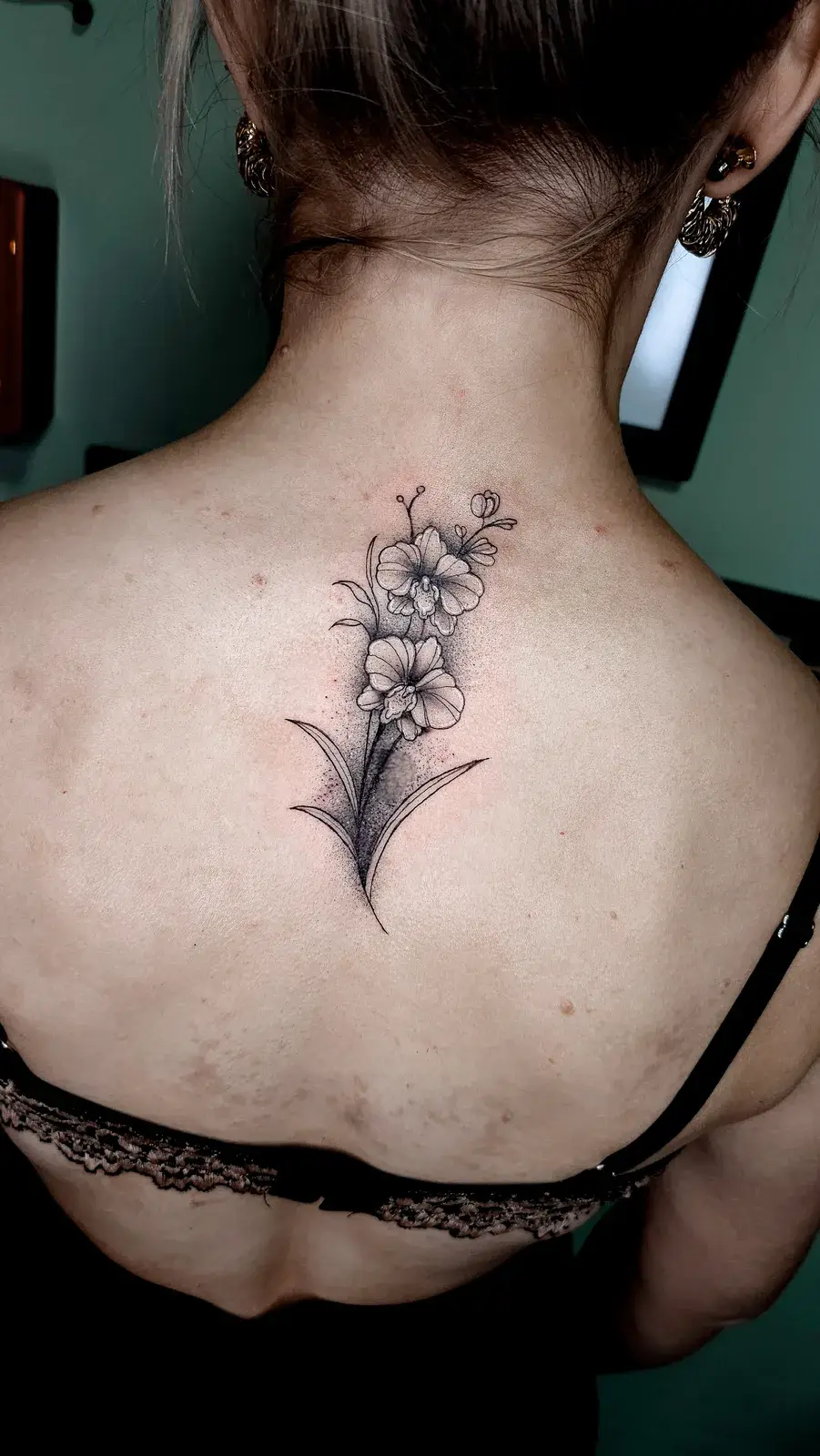 Cobertura de tatuagem com ramo de flores em traço fino na parte alta das costas