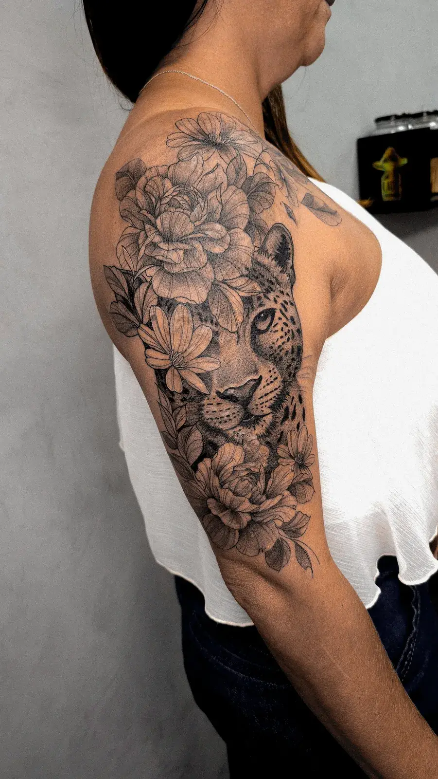 Cobertura em braço fechado com rosto de onça entre flores em preto e cinza