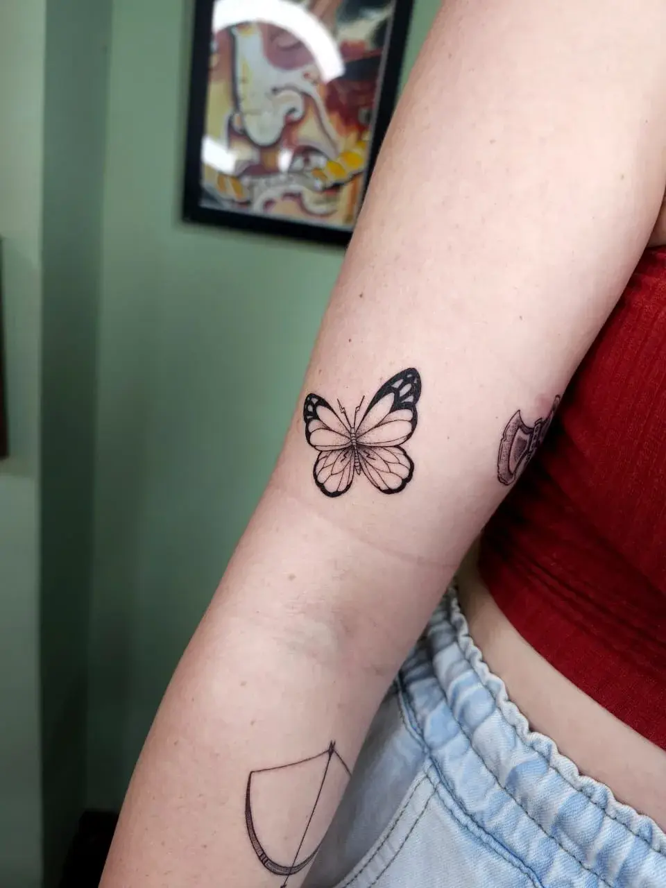 Tatuagem fine line de borboleta com asas detalhadas no braço