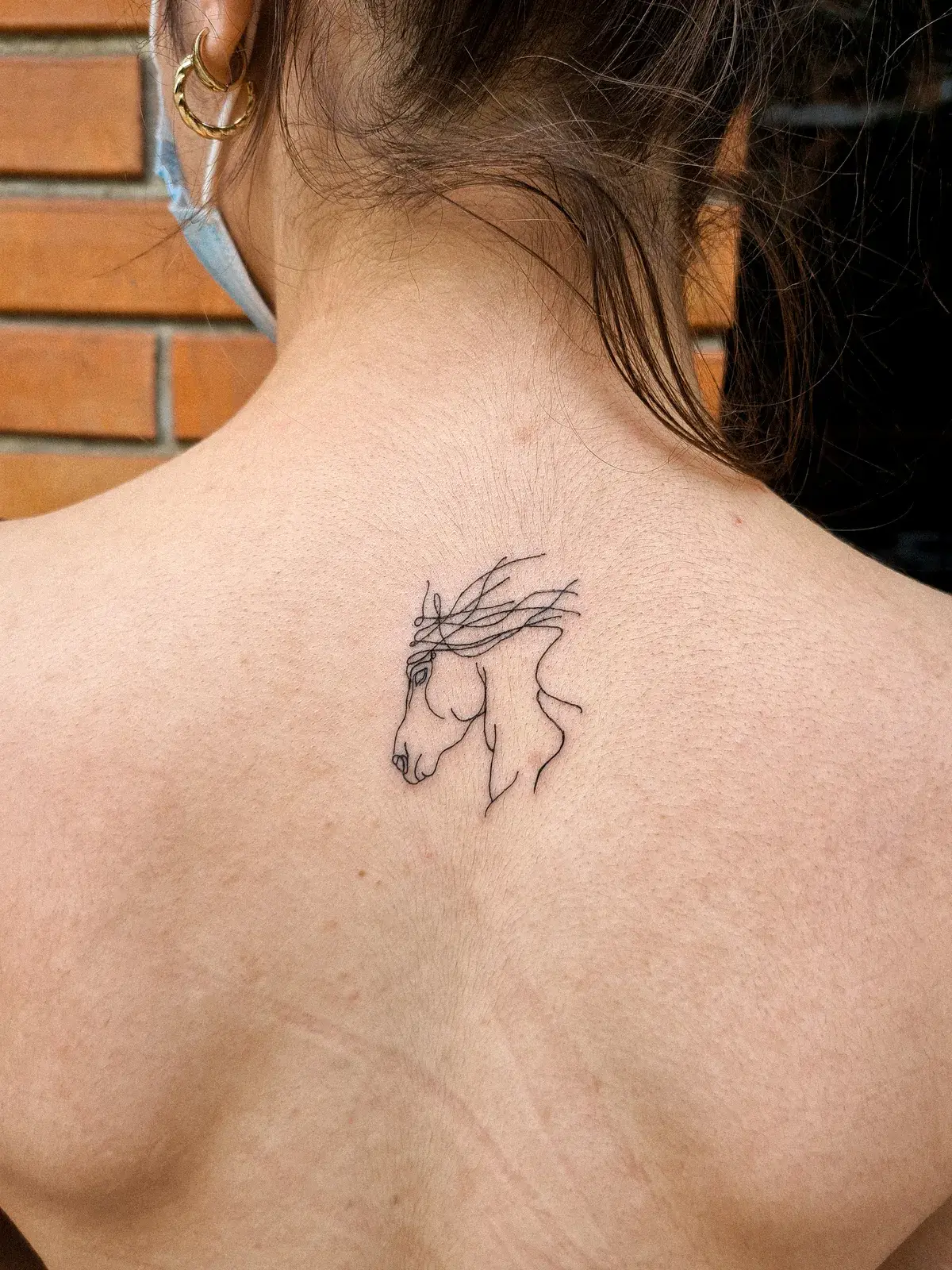 Tatuagem fine line de cabeça de cavalo em traço contínuo nas costas