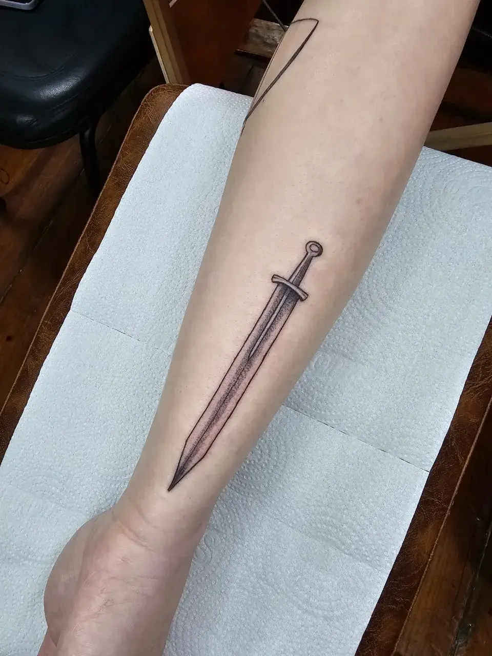 Tatuagem fine line de espada em pontilhismo no antebraço