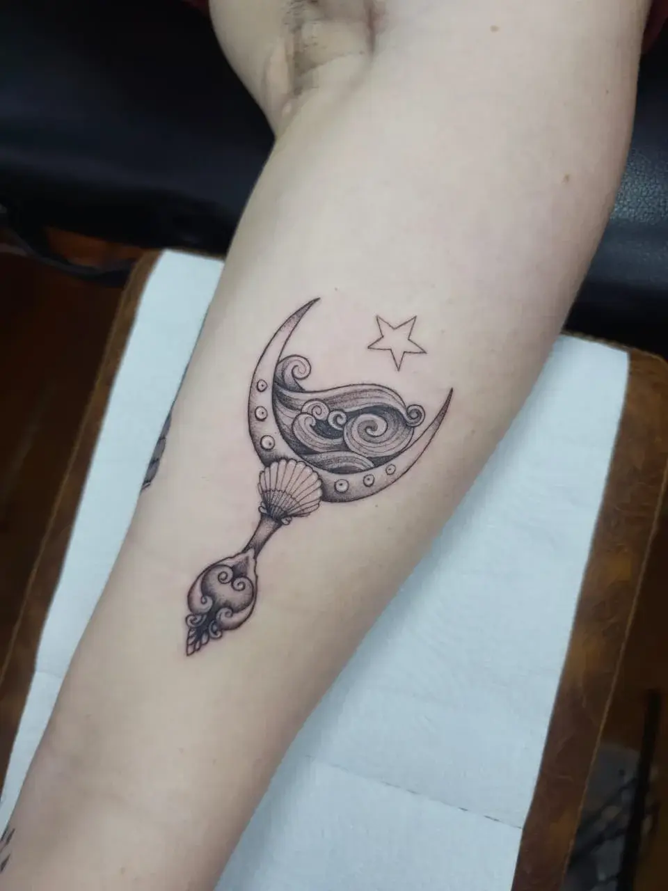 Tatuagem fine line do espelho de Iemanjá com lua crescente e estrela, no antebraço