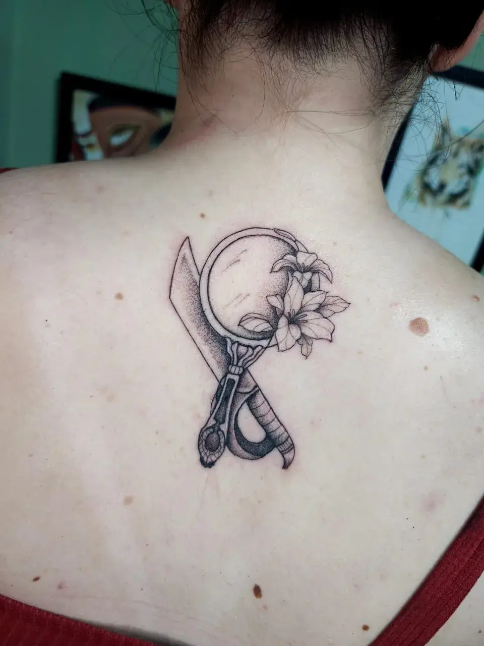 Tatuagem fine line de espelho de mão, tesoura e flores nas costas