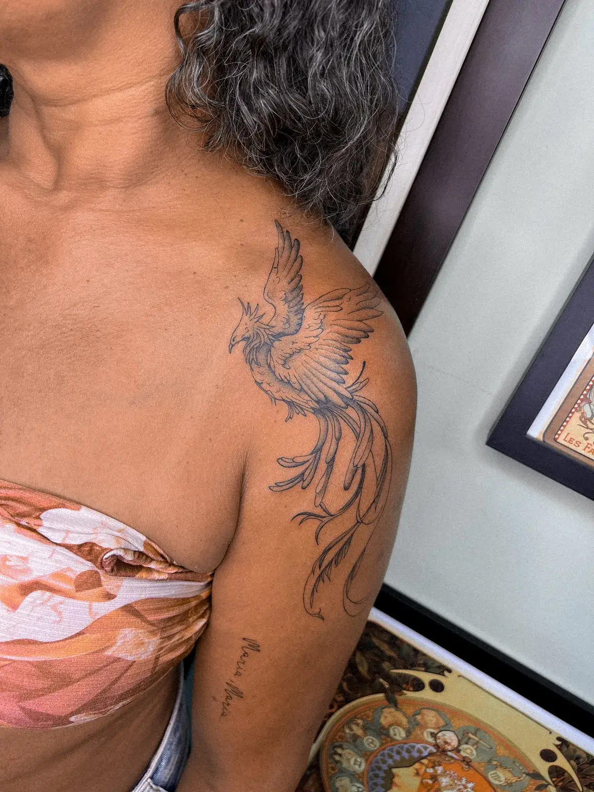 Tatuagem fine line de fênix em voo no ombro e nas costas