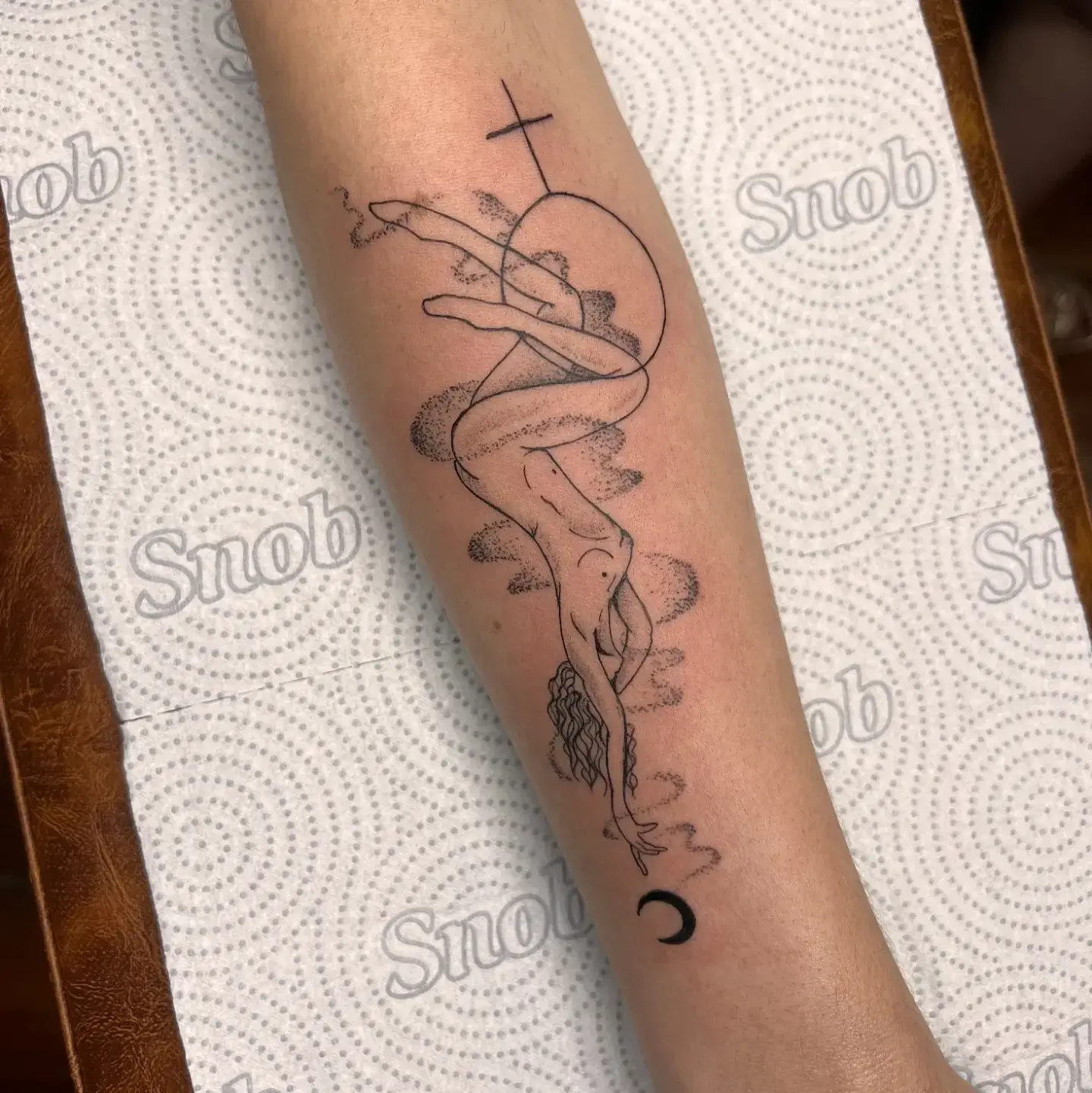 Tatuagem fine line de figura feminina entre nuvens pontilhadas no antebraço