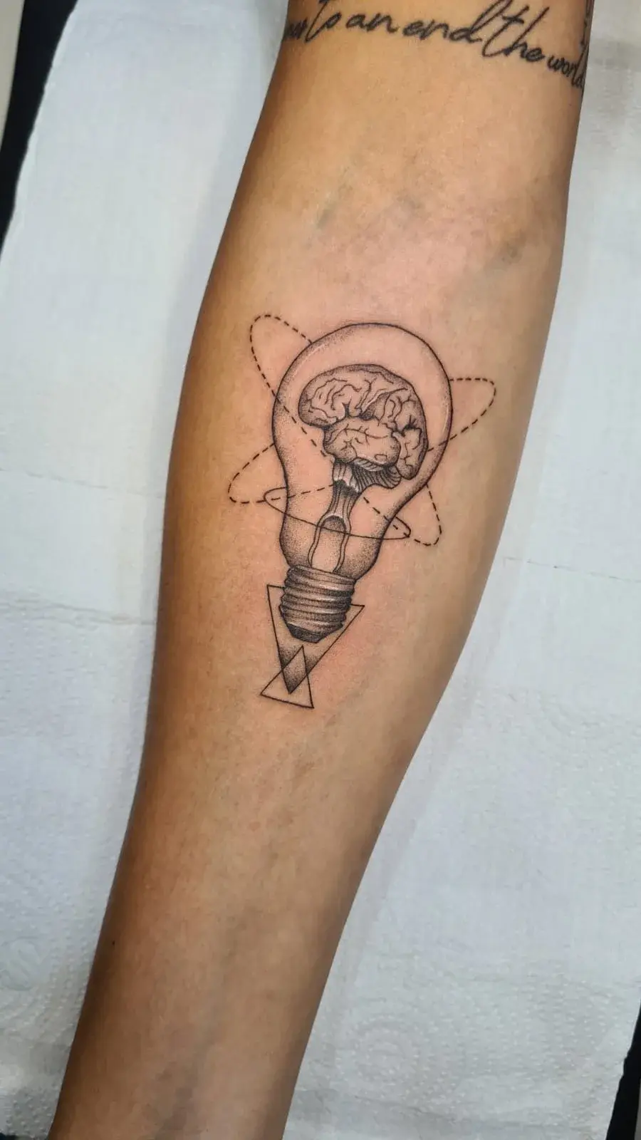 Tatuagem fine line de lâmpada com cérebro e geometria, no antebraço