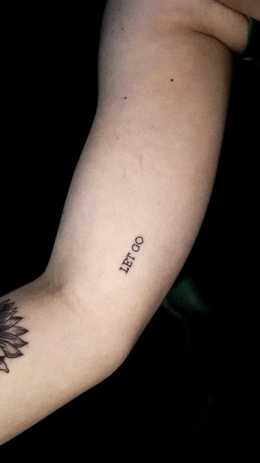 Tatuagem fine line com o lettering Let Go no braço