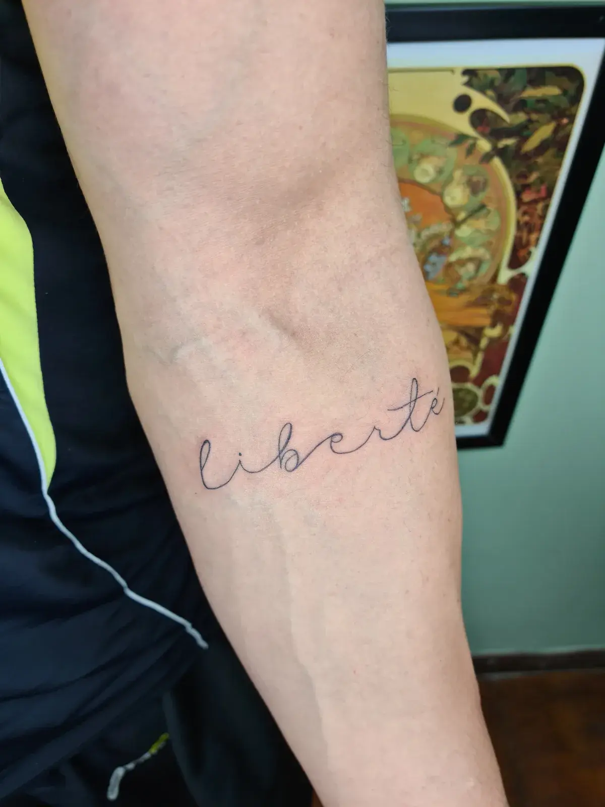Tatuagem fine line com o lettering liberté no antebraço