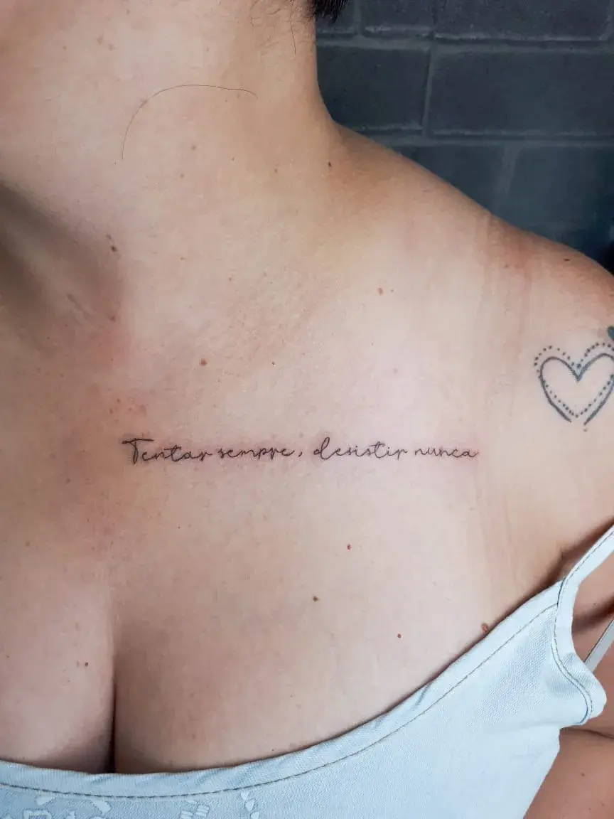 Tatuagem fine line com o lettering Tentar sempre, desistir nunca na clavícula