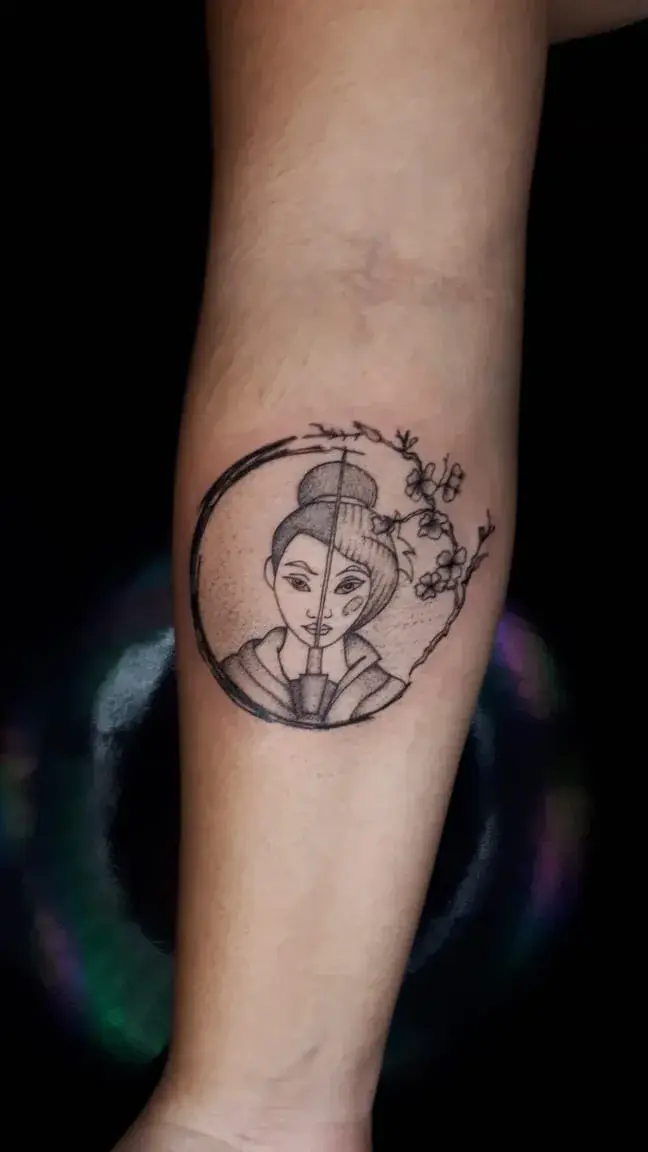 Tatuagem fine line da Mulan dentro de círculo enso com ramo de cerejeira, no antebraço