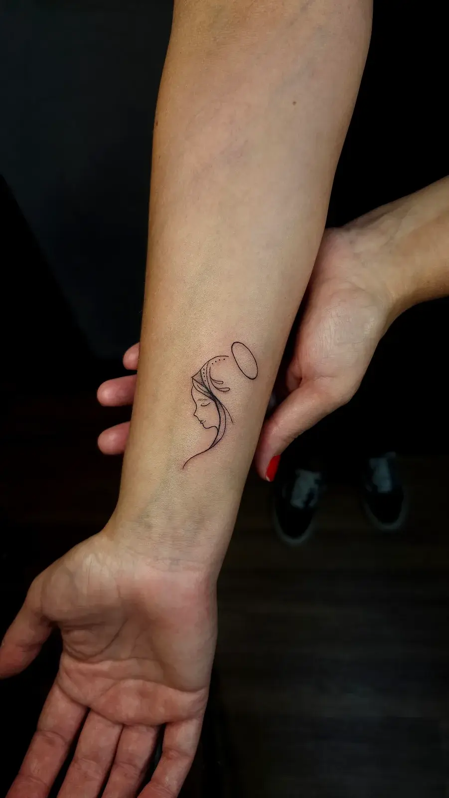 Tatuagem fine line de Nossa Senhora em rosto minimalista de linha contínua, no antebraço