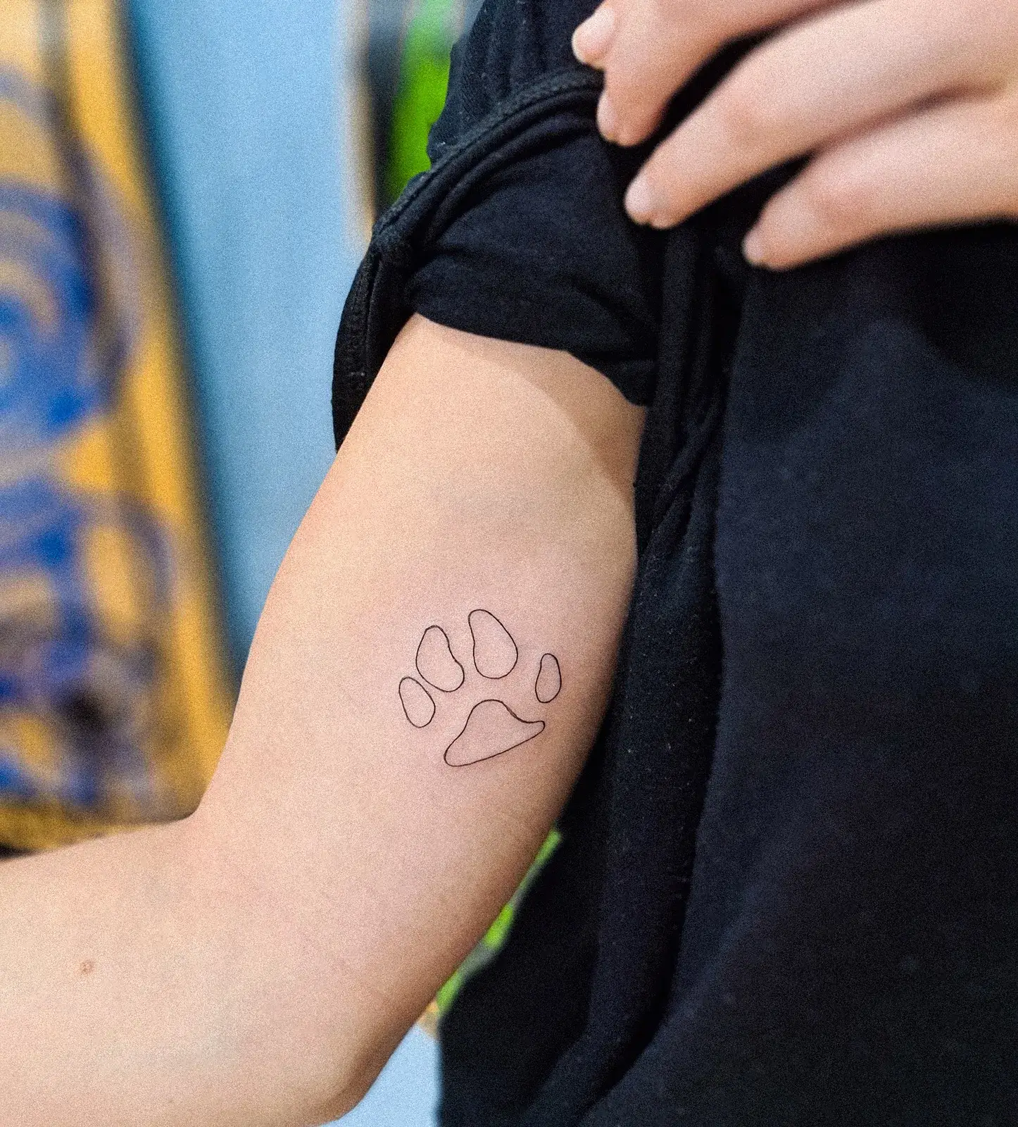 Tatuagem fine line de patinha de cachorro só em contorno, no braço