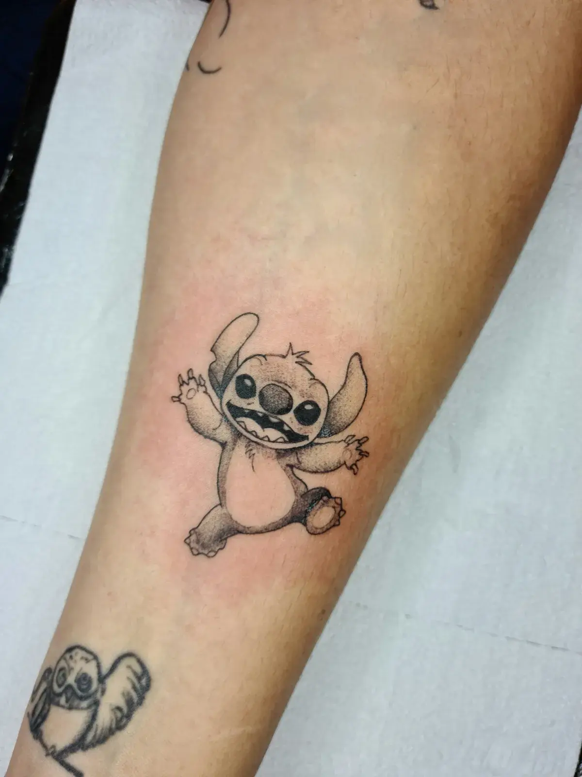 Tatuagem fine line do Stitch, de Lilo & Stitch, em pontilhismo no antebraço