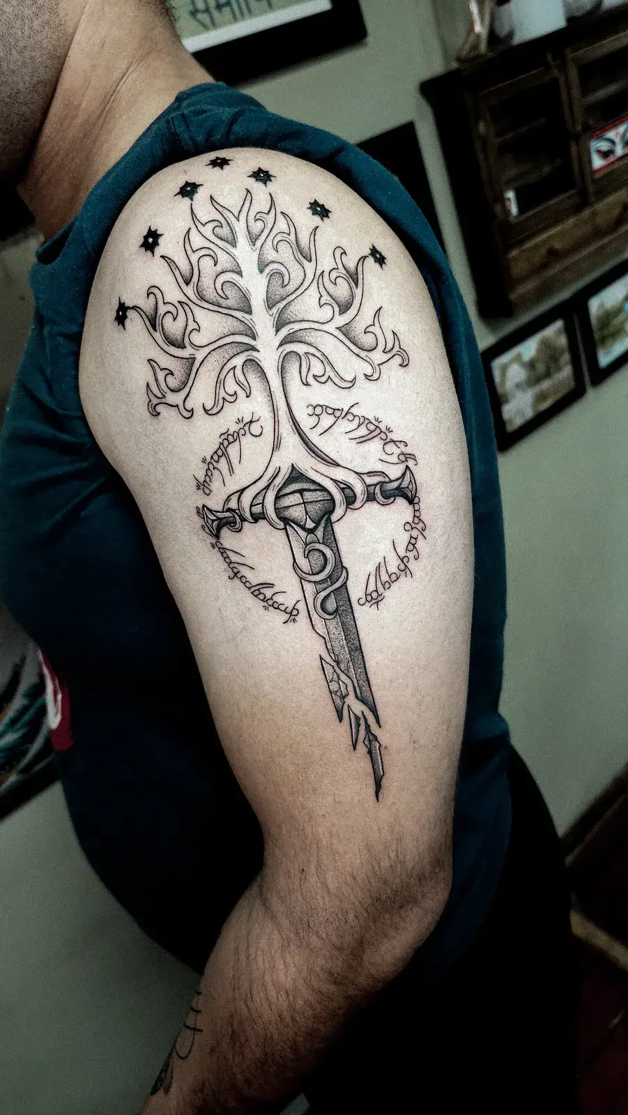 Tatuagem de árvore branca com espada e inscrições élficas no ombro