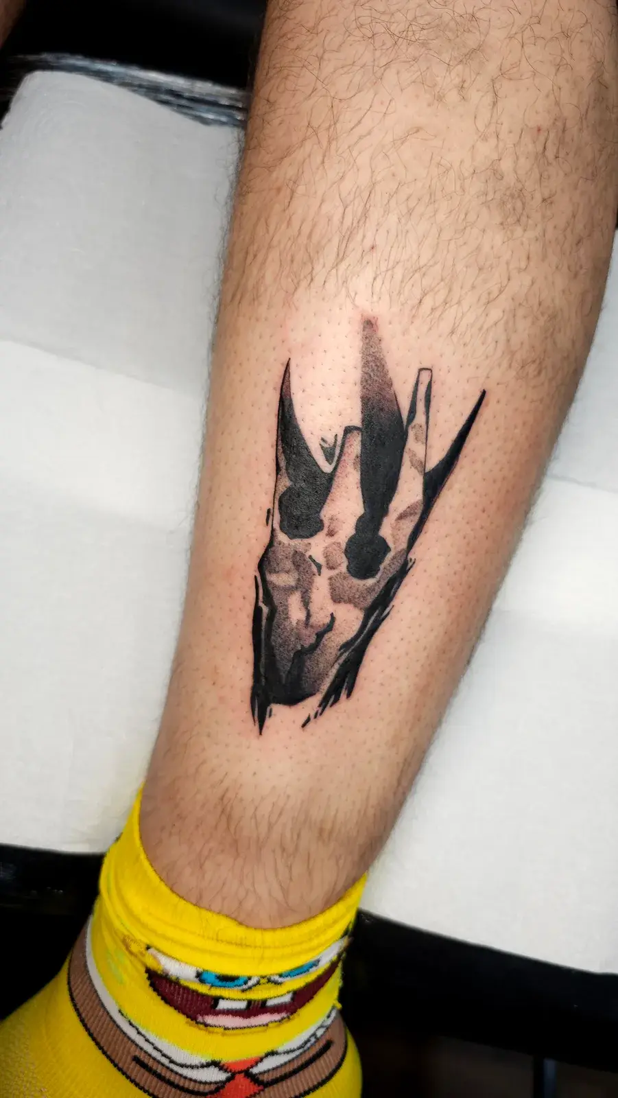 Tatuagem geek de Disco Elysium com o símbolo de Volition em blackwork na panturrilha