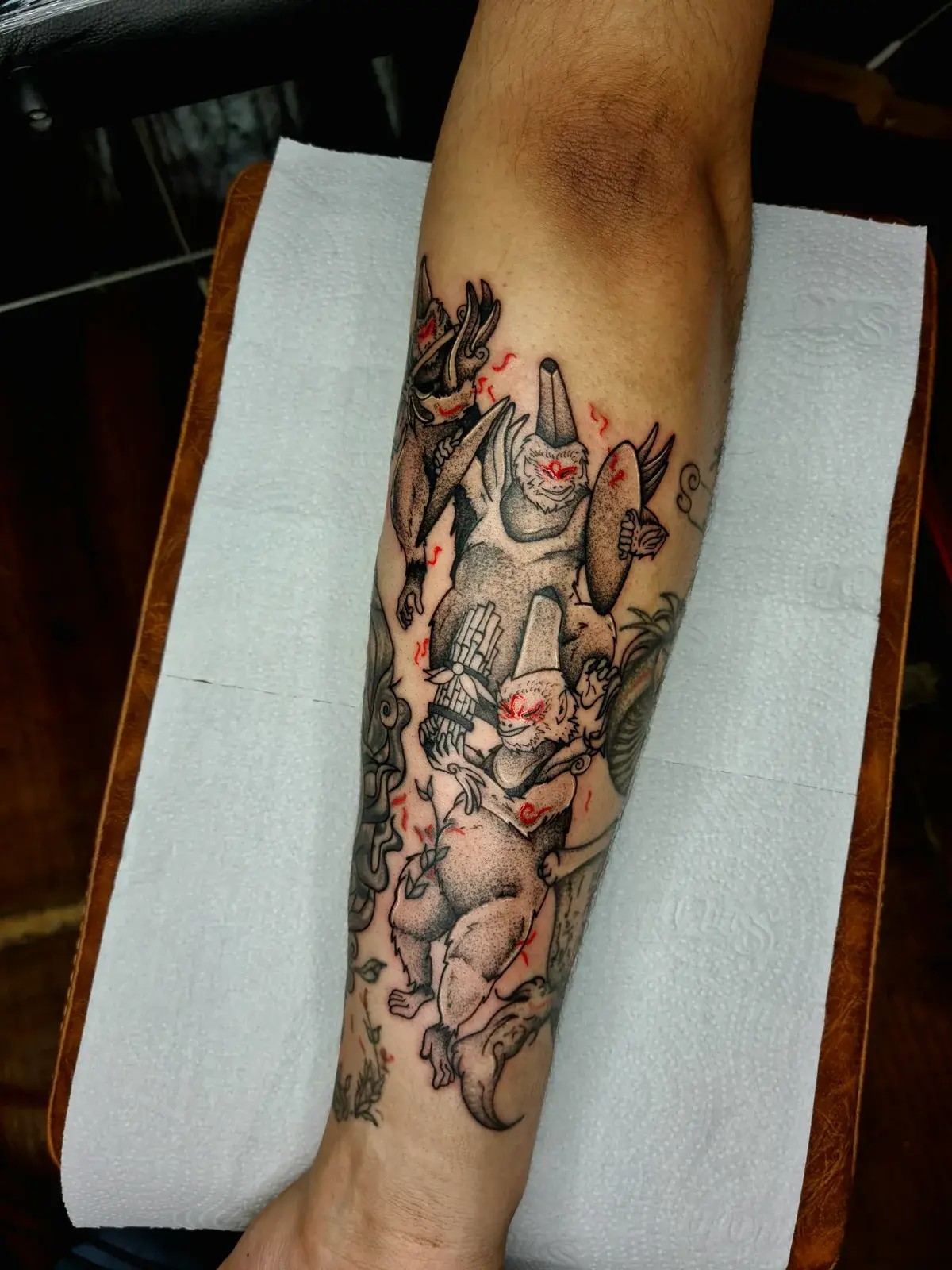 Tatuagem geek de Okami com os Hanagami em pontilhismo e respingos vermelhos no antebraço