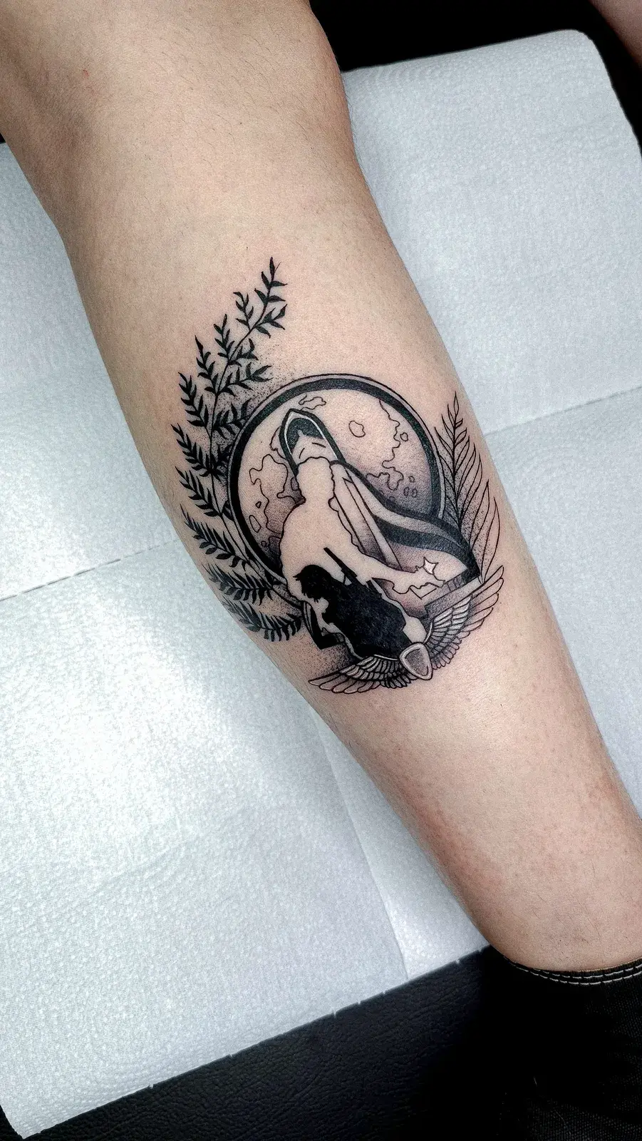 Tatuagem geek da Ellie, de The Last of Us, em moldura circular com blackwork na panturrilha